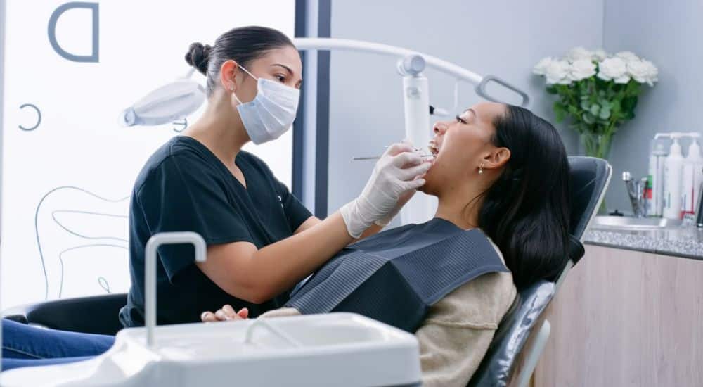 Dentiste, femme et patiente lors d’une consultation, avec outils dédiés à l’hygiène bucco-dentaire, réforme 100% santé