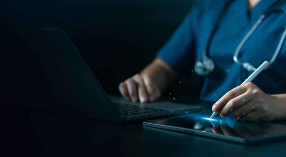 Médecin se servant d'un ordinateur et d'une tablette. Clinique d'oncologie buccale intelligence artificielle