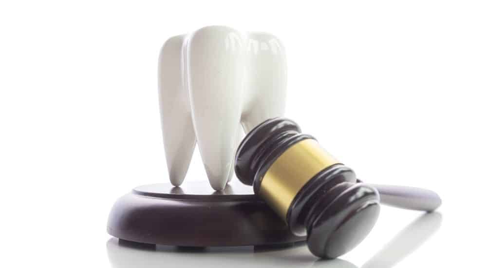 Dent et marteau sur fond blanc, sinistralité des chirurgiens-dentistes