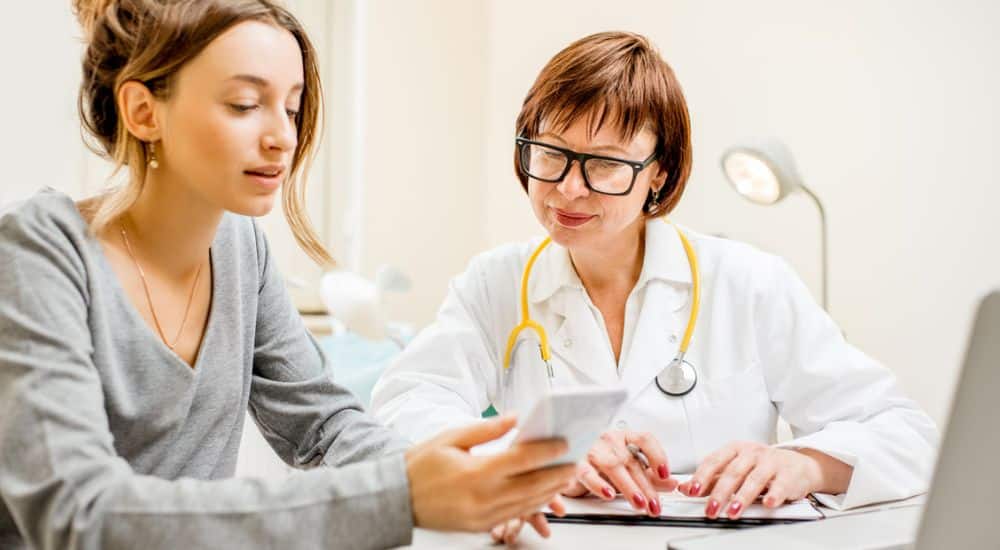 Patiente et médecin devant smartphone, application e-carte Vitale