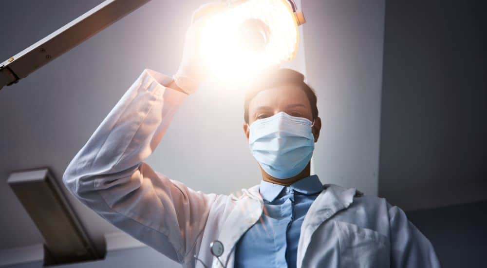 Chirurgiens-dentistes tenant lampe au-dessus de son patient, permanence des soins, urgences dentaires