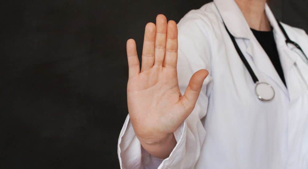 Femme médecin faisant arrêt signe avec sa main, refus de soins dentaires, refus soins dentaires