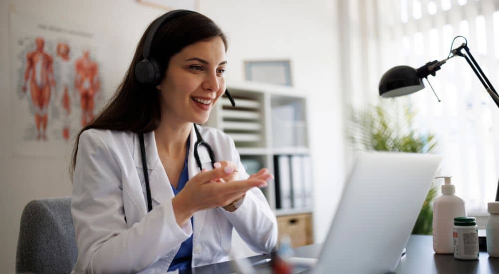 Femme médecin devant son ordinateur en téléconsultation avec un patient