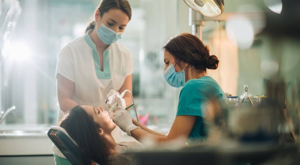 Dentiste et son assistante effectuant des soins dentaires sur la jeune femme. Assistant dentaire salaire