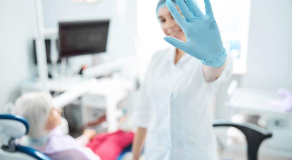 Femme dentiste faisant un geste de la main pour dire stop, grève des chirurgiens-dentistes belges