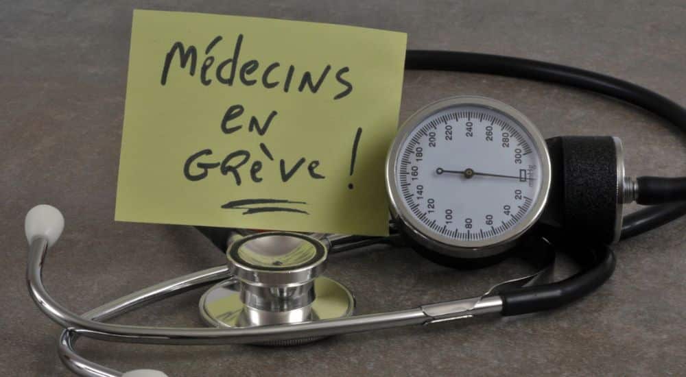 Post-it posé sur un stéthoscope, avec l'inscription médecins en grève. Mobilisation des soignants