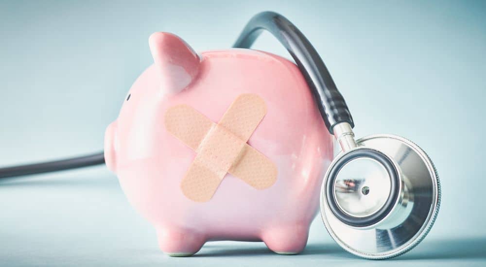 Tirelire avec un pansement et un stéthoscope, doublement des franchises médicales