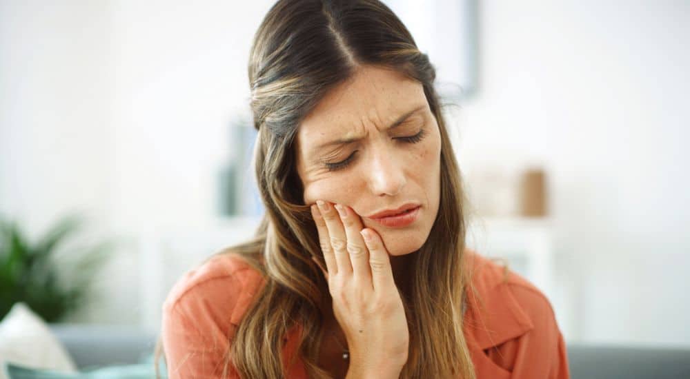 Femme se tenant la joue, mal de dents, évaluation du risque carieux