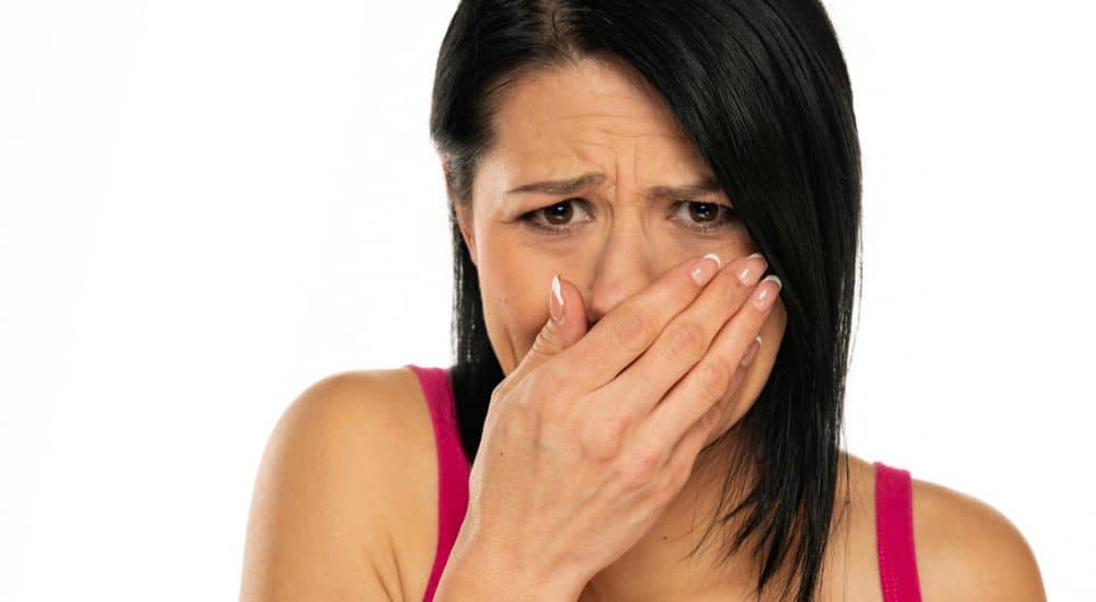 Jeune femme gênée, se cachant les dents avec une main