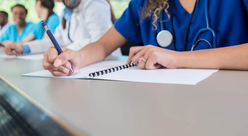 Étudiante en santé écrivant sur un bloc. Réforme des études de santé