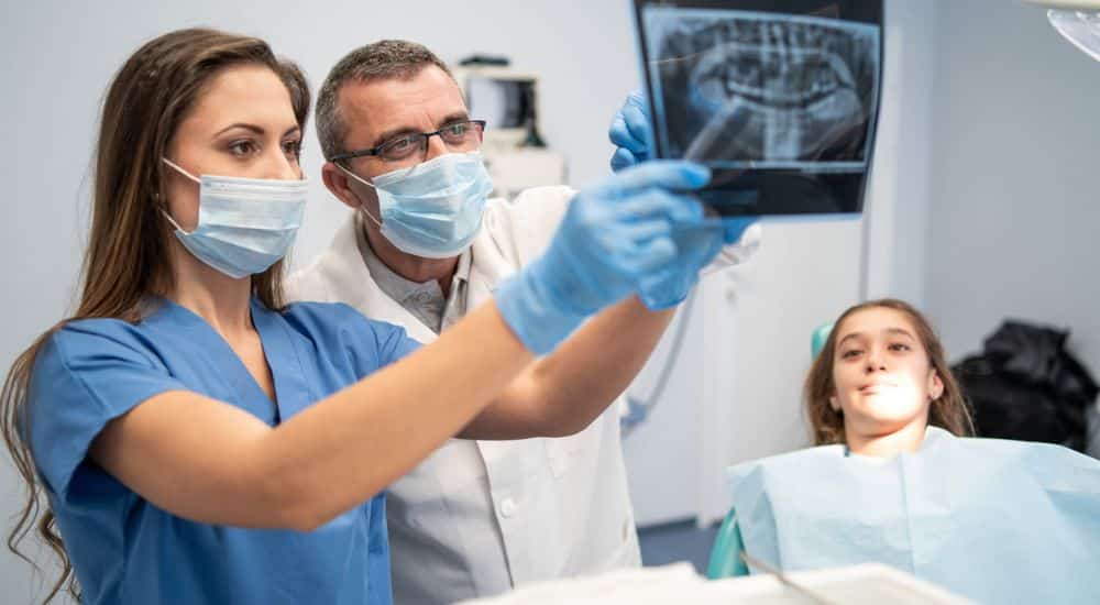 Assistante en santé bucco-dentaire avec un chirurgien-dentiste devant une radiographie dentaire