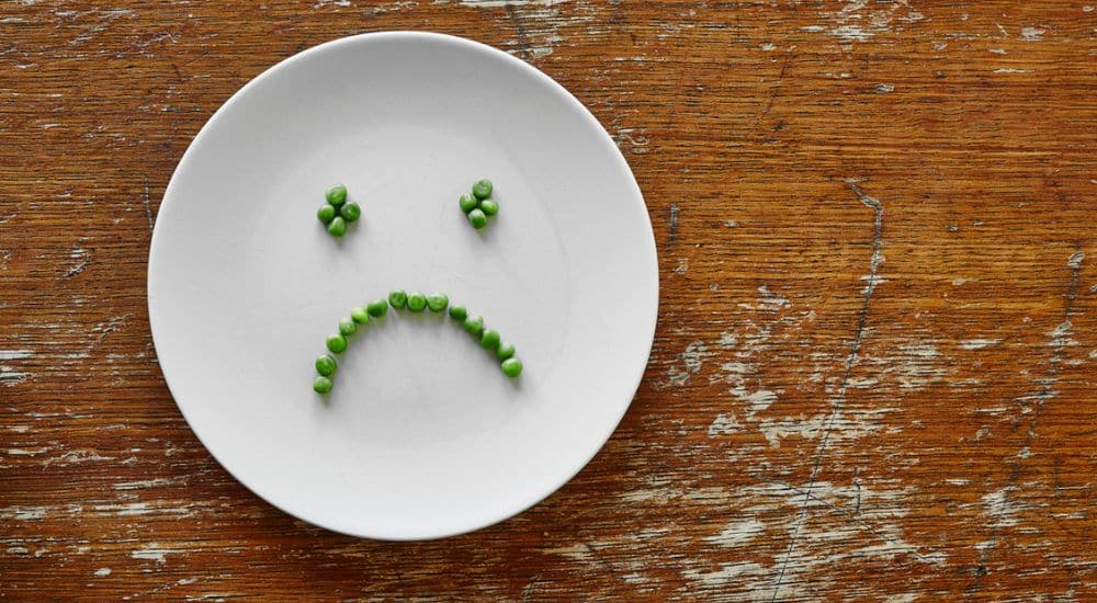 Tête triste faite en petits pois dans une assiette. Semaine nationale de la dénutrition