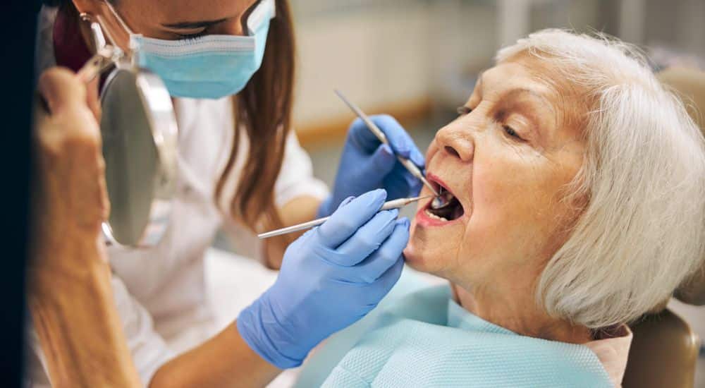 Femme âgée chez le dentiste. Traitement de carie avec des outils conventionnels. Traitement sans forage des caries chez les personnes âgées