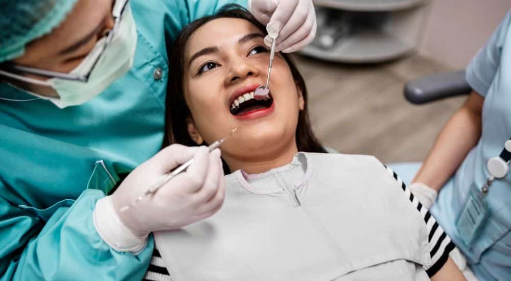 Jeune femme se faisant vérifier les dents par un chirurgien-dentiste, traitement des caries dentaires