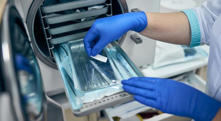 Mains gantées, préparant le matériel de dentisterie à stériliser. Suspension d’un centre dentaire par l’ARS